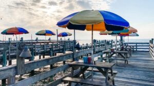 Colorful umbrellas over picnic tables on a boardwalk over the ocean