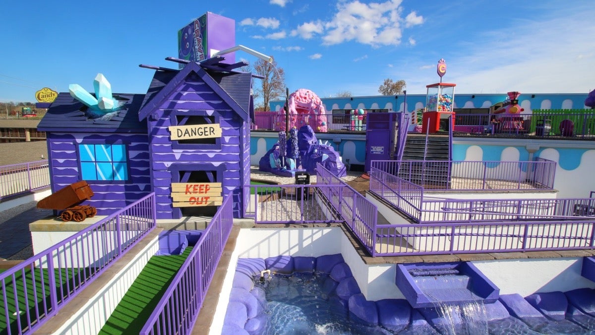 Purple house with a water feature around it at a mini golf course