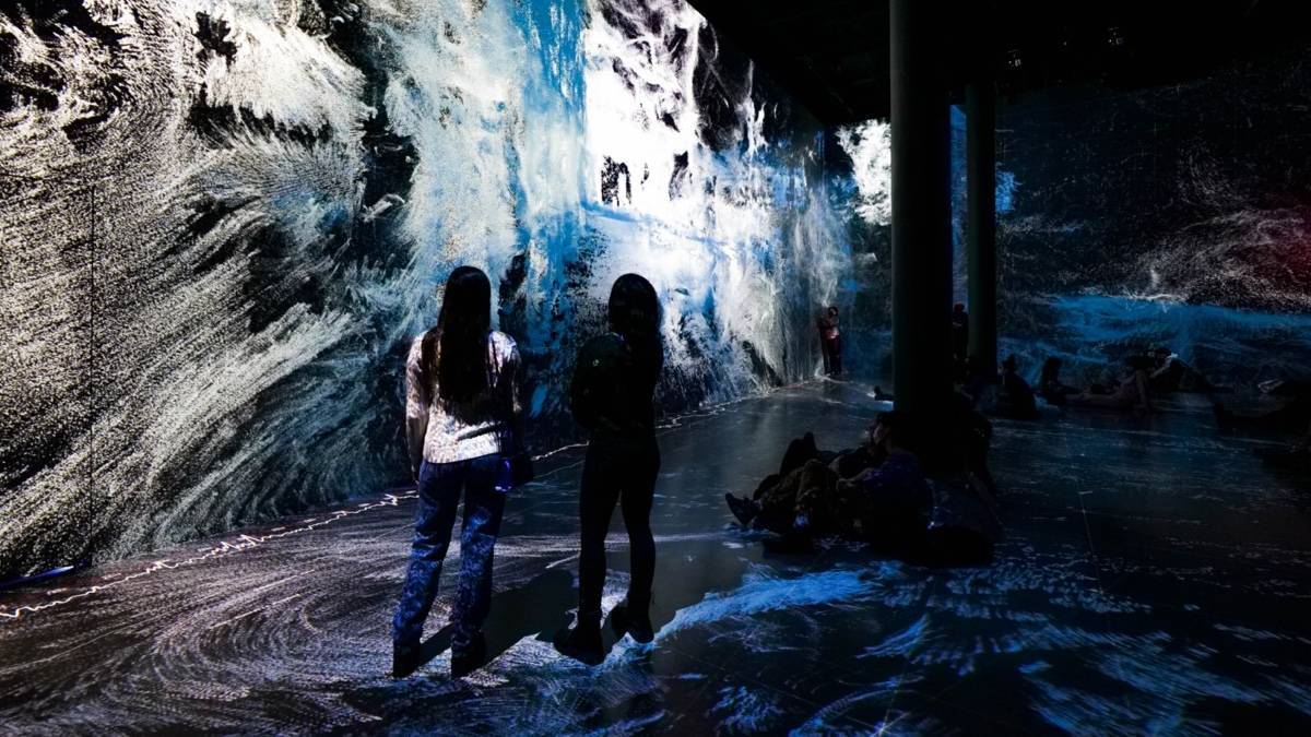 Two people standing in a room looking at an art installation that takes up an entire wall