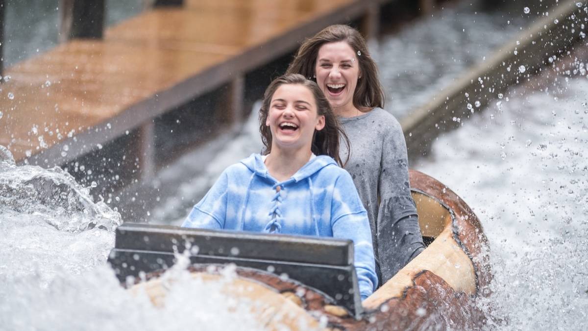 Two girls riding a log flume ride splashing through water