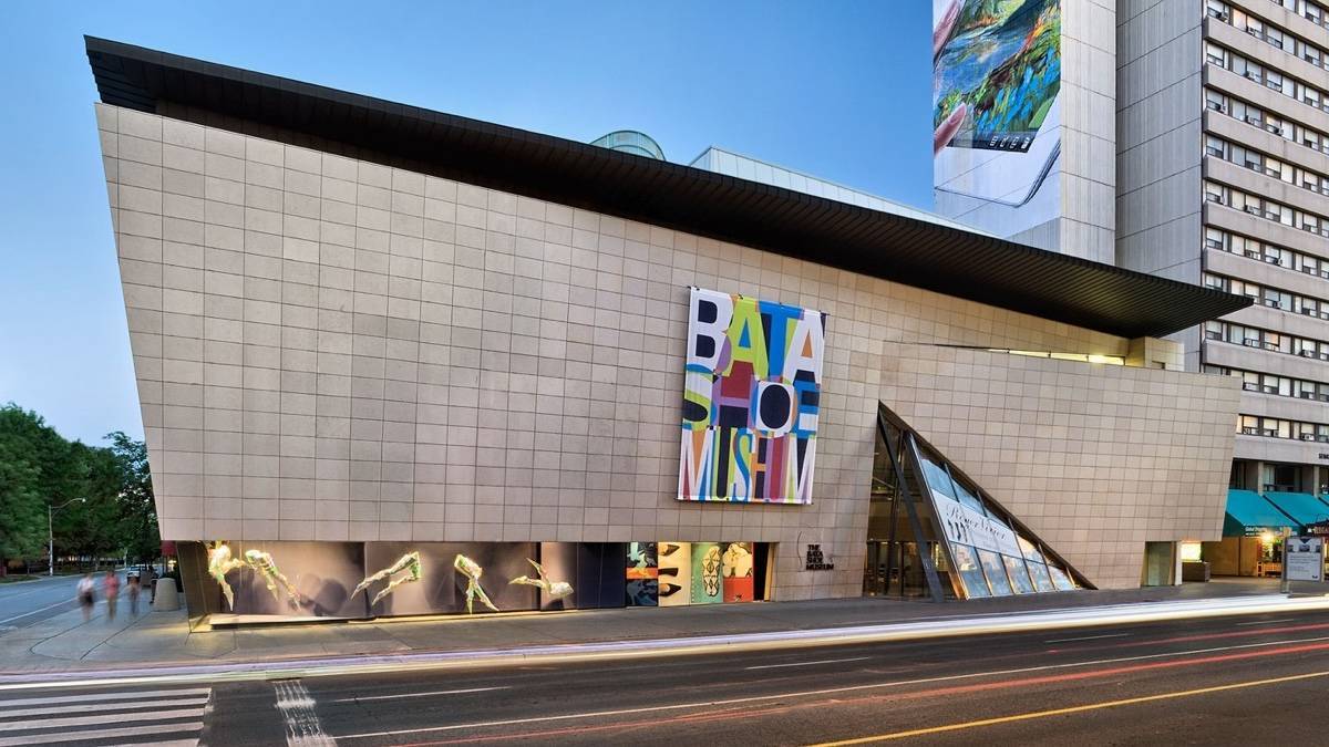 Exterior of Bata shoe museum, angular white stone building with a colorful sign reading Bata Shoe Museum under a blue sky