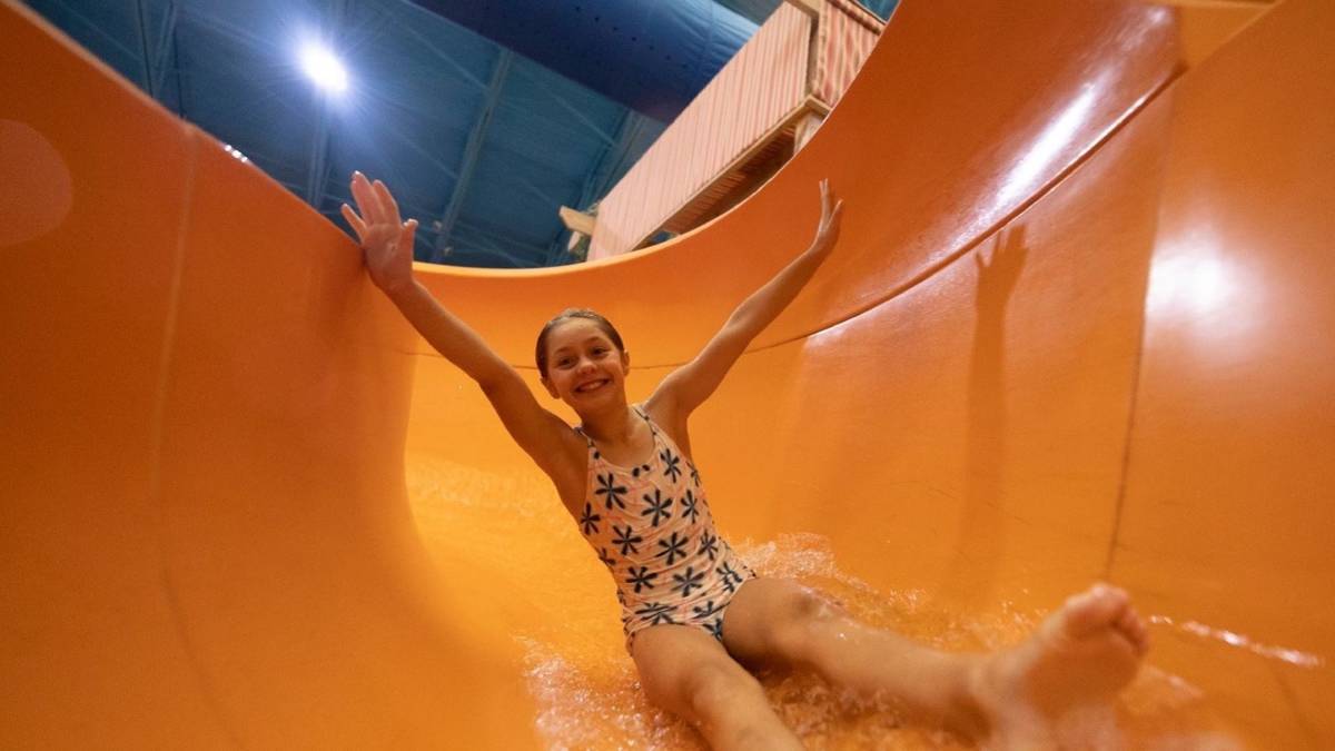 A girl sliding down a water slide with her hands up