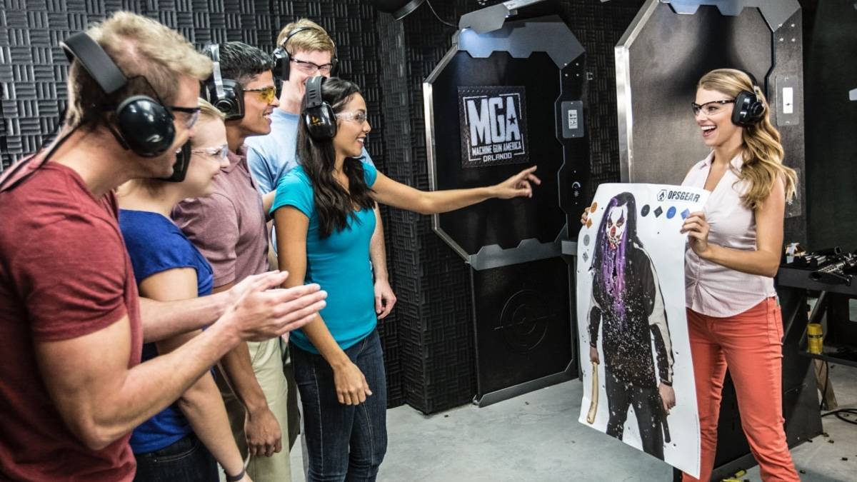A group of people with noise cancelling earphones looking at a woman holding up a target practice paper
