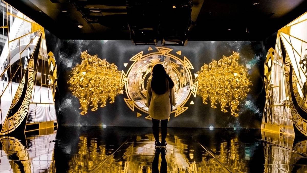 Large walls of digitized gold, black, and white art with a single person standing in the foreground looking at it all