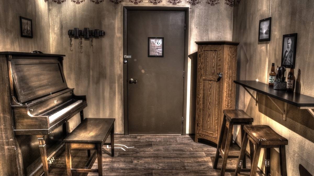 Interior of an escape room with a piano and shelf with bar stools