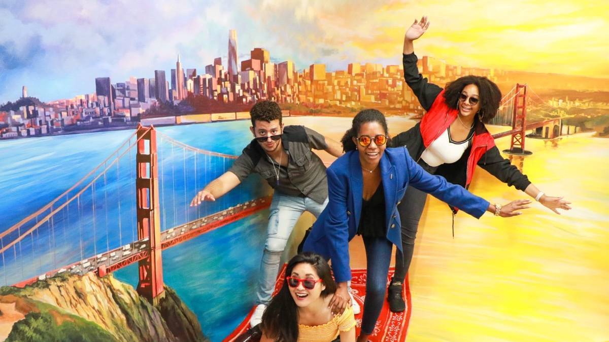 Four people inside an illusion of riding a magic carpet over the golden gate bridge