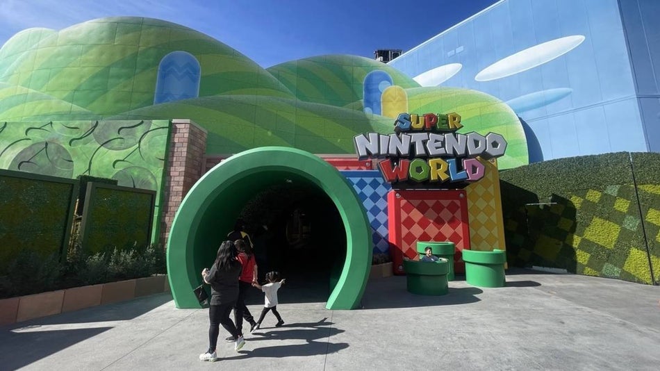 Entrance to Super Nintendo World with a green tunnel surrouned by animated green hills