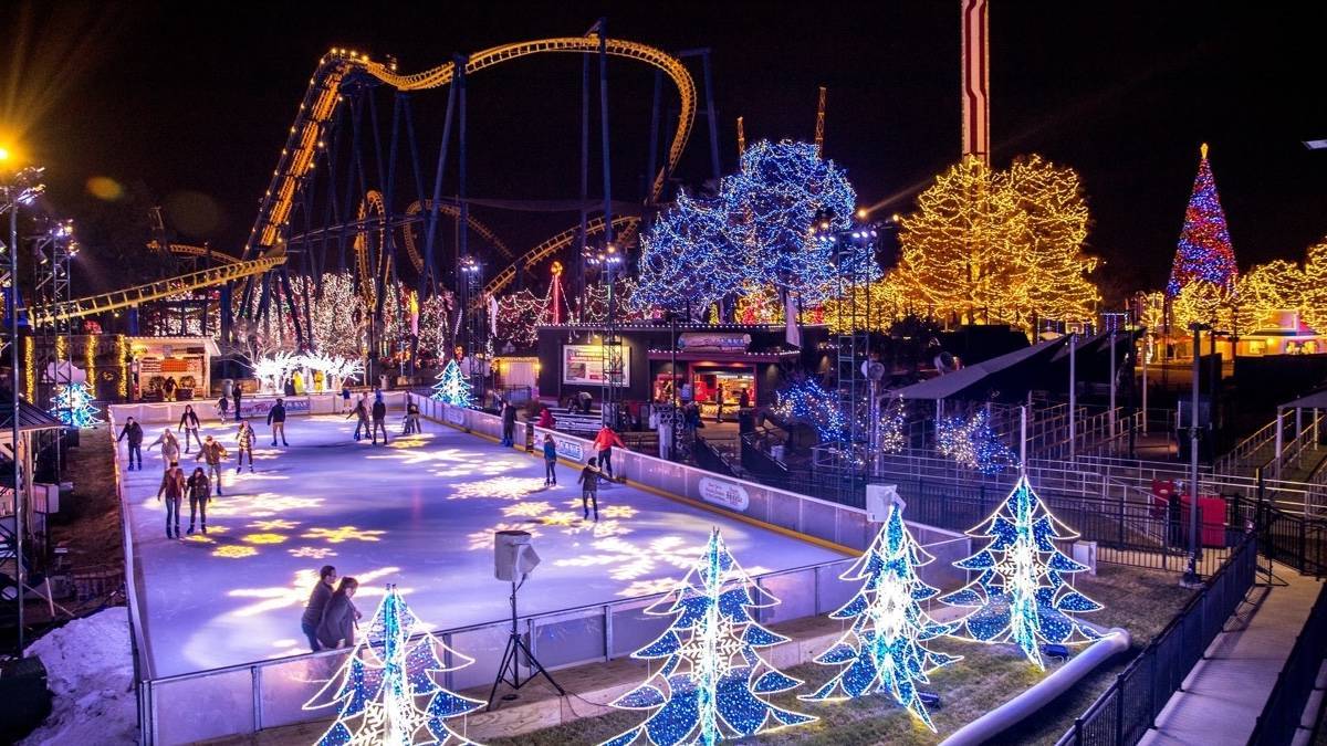Wide angle shot of a ice rink with lots of christmas lights and decor surrounding it