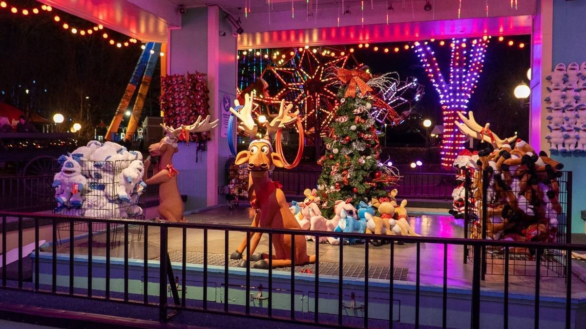 Two mannequin reindeer in a christmas setting, one has a shopping cart full of yeti stuffed animals and the other is sitting in front of a christmas tree