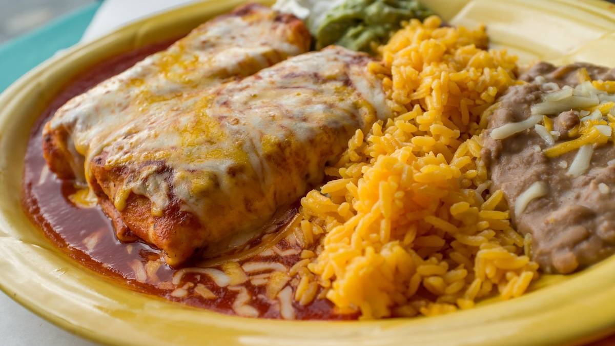 burrito enchilada style with rice ad beans on a yellow plate