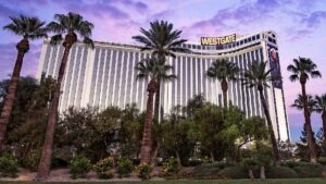 Exterior view of the Westgate resort in Las vegas under a purple dusky sky with palm trees in the foreground