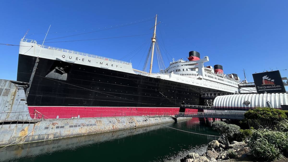 Exterior wide shot of an old steam ship with black white and red paint on it