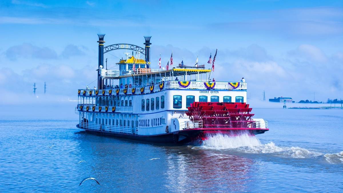 Large cruise boat named Creole Queen on the water with a bright blue sky behind it in New Orleans, Louisiana