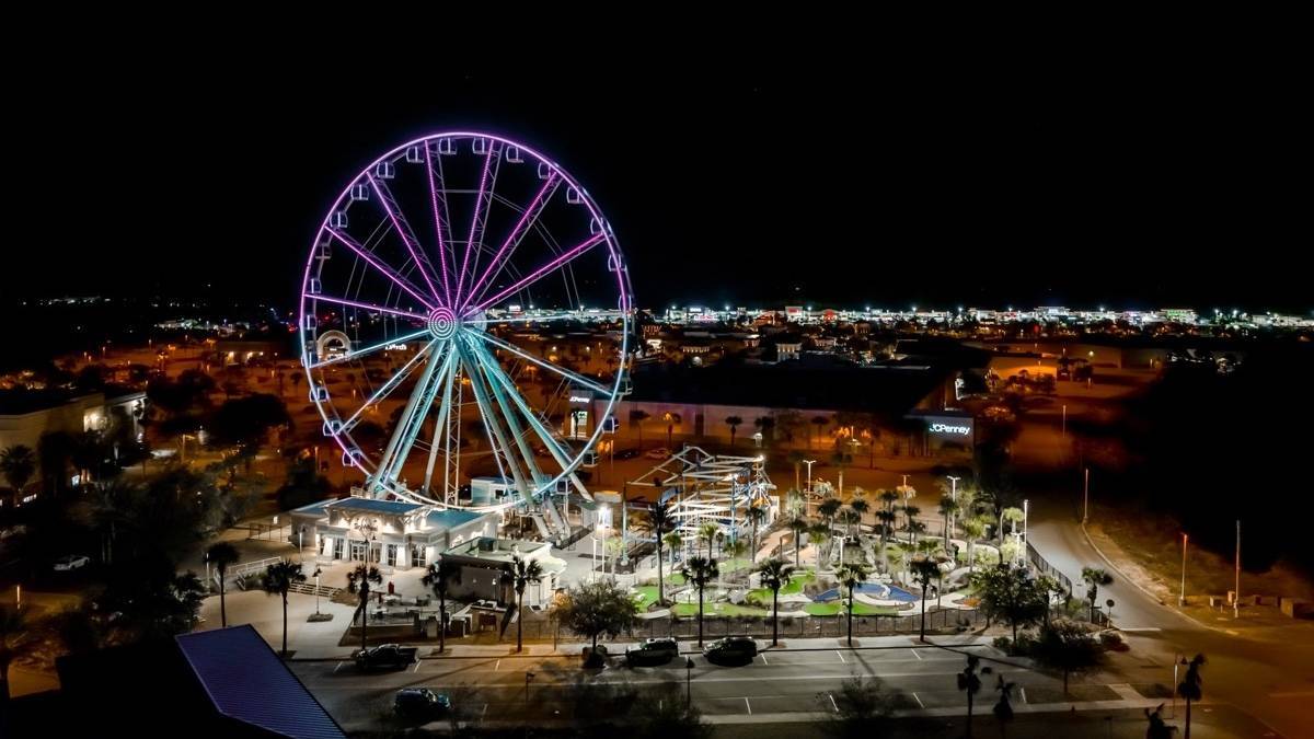 Aerial shot of a ferris wheel at night a beach side town