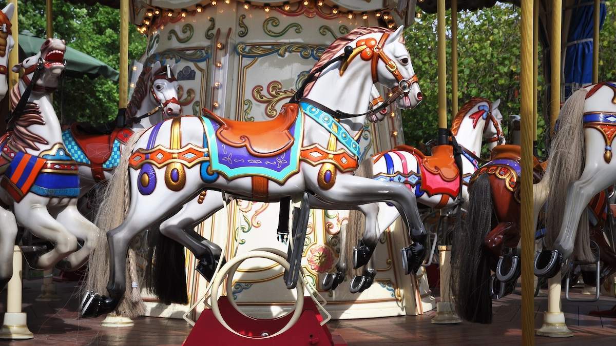 White horses on a vintage merry go round at a county fair