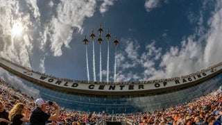 Wide angle of stadium seating at Daytona international speedway looking up at the sky as 6 fighter jets fly over the race track