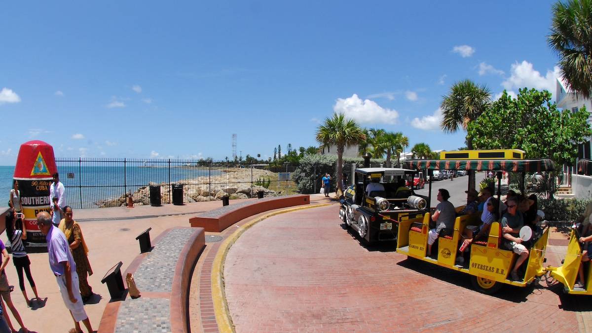 Yellow train tram on a paved road next to the southern most point in the US