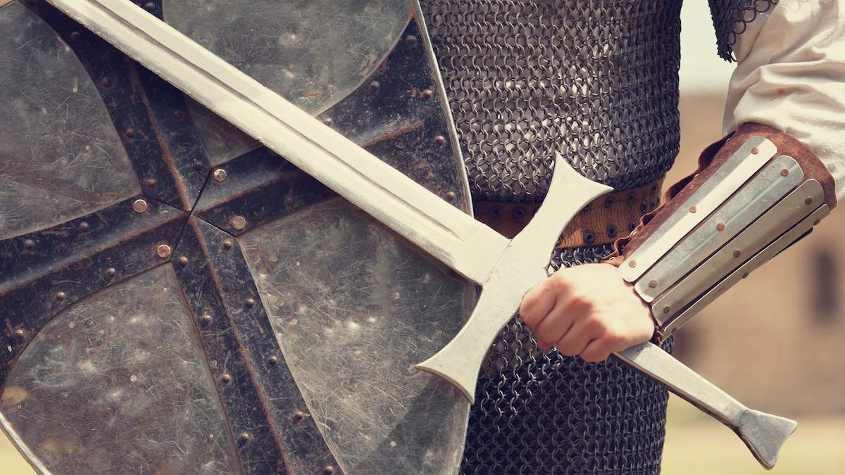 Person with medieval armor holding a shield and sword