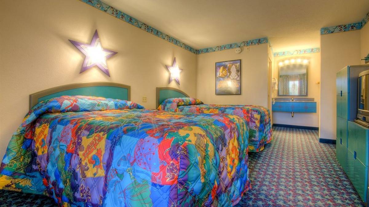Interior room with two colorful beds with star lights on the walls and blue border at Disney’s All Star Movies Resort - Orlando, Florida, USA