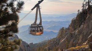 Aerial tram coming up a metal line with desert mountains in the background