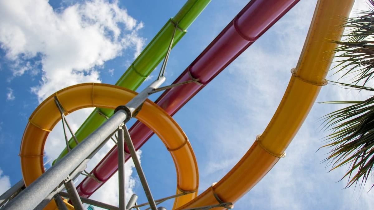 Looking up at yellow, red, and green water slides under a blue sky