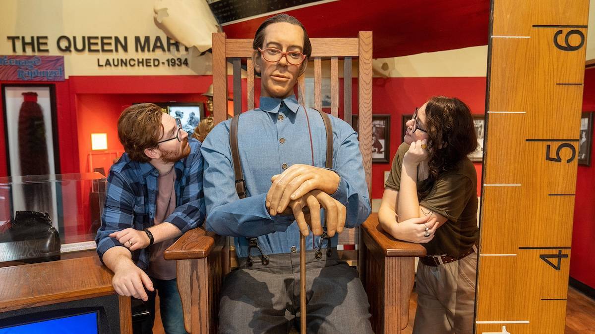 Two people gazing at a large figurine of a man sitting in a rocking chair at Ripley's Belive it or Not
