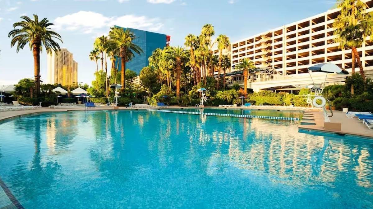 Exterior shot of pool surrounded by palm trees next to a hotel in Las Vegas