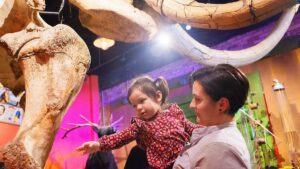 Woman holding a child next to a large dinosaur at Ripley's Believe it or Not