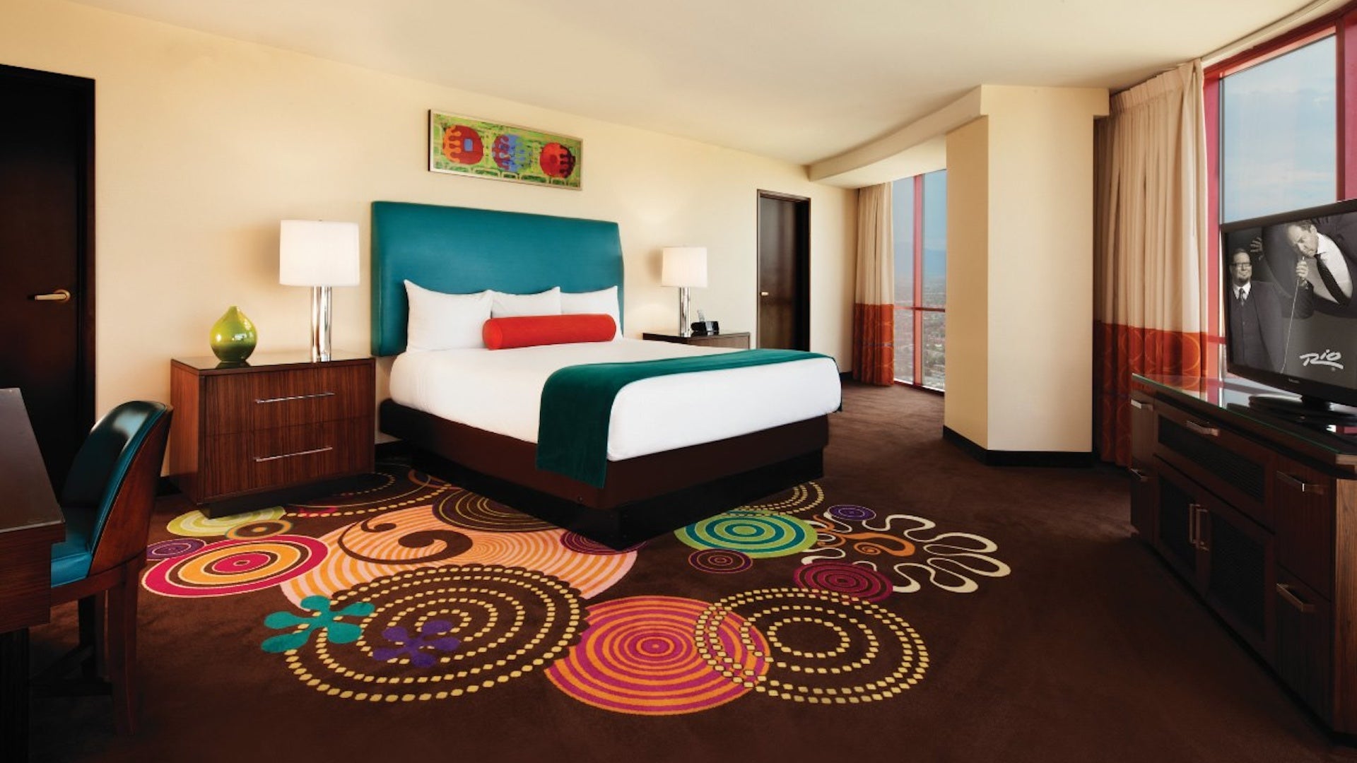 hotel room with a white and teal bed and chocolate floors with colorful swirls