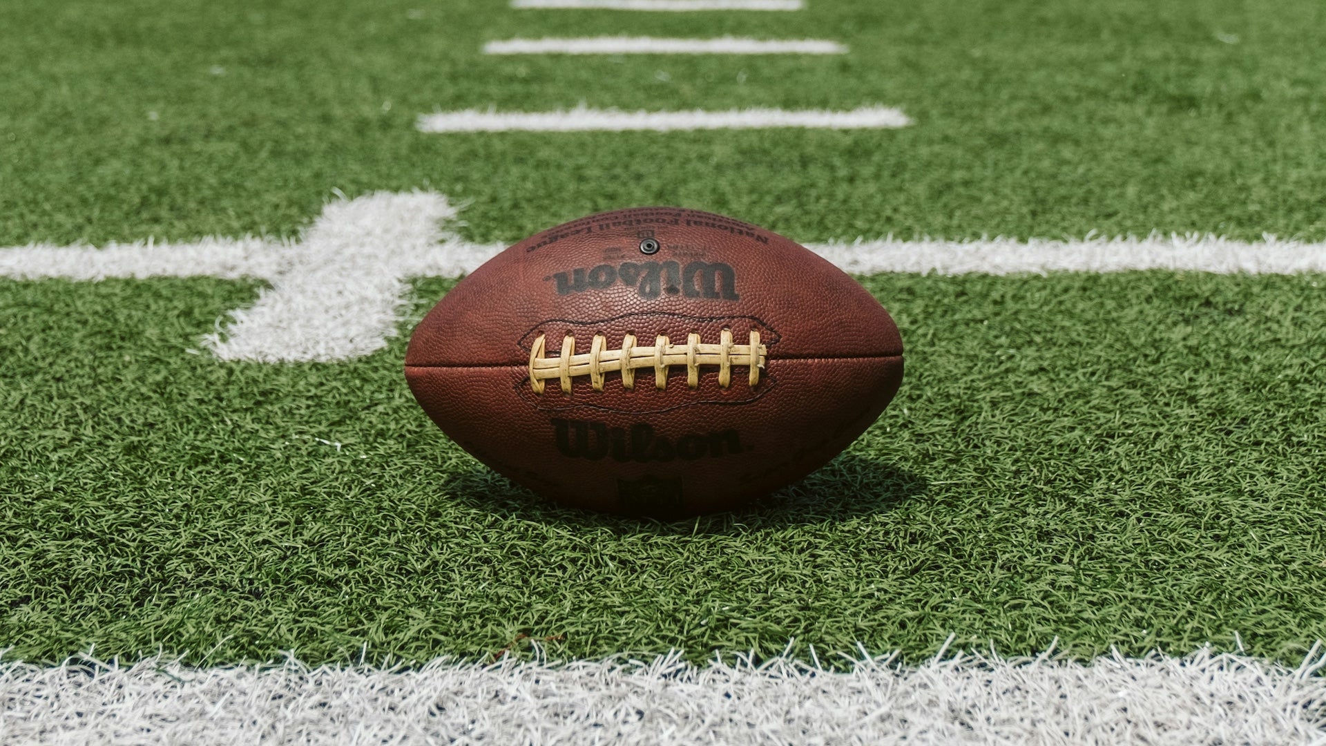Wilson football sitting on a green football field