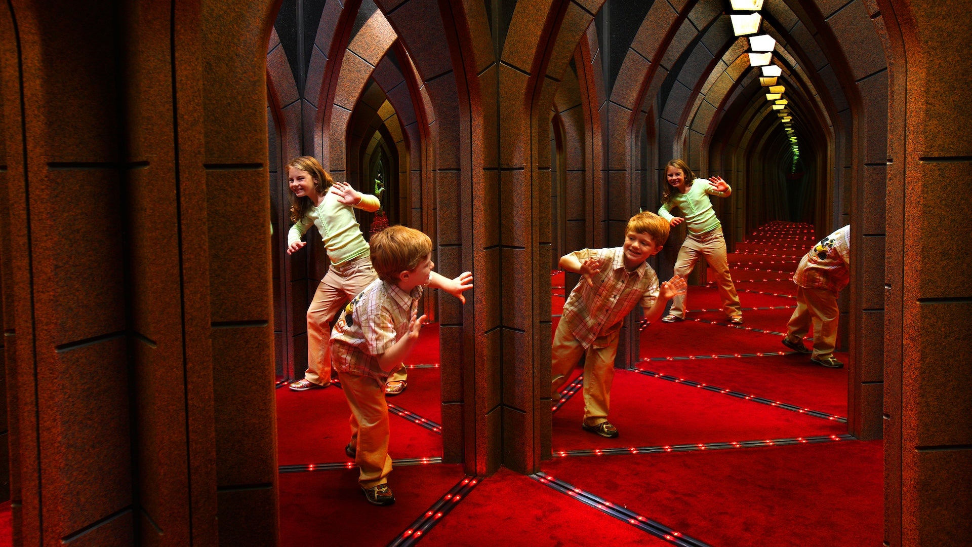 A boy and a girl playing in a mirror maze room
