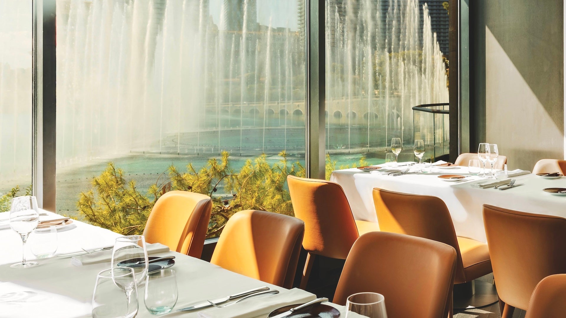 Chairs and white tables with a window view of the Bellagio fountains