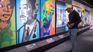 A person looking at an exhibit on a wall full of people's portraits