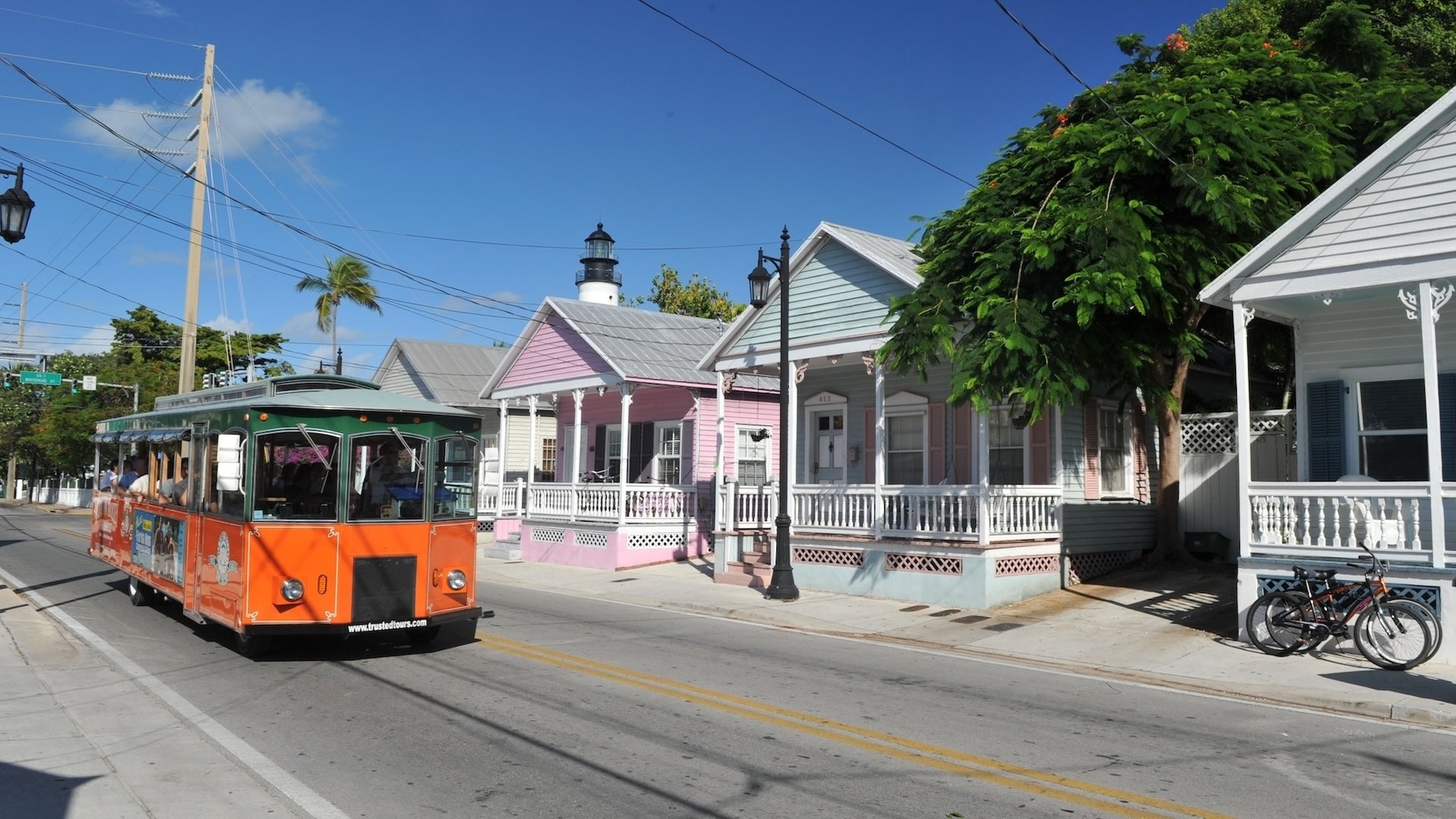 red trolley bus along white and pink houses