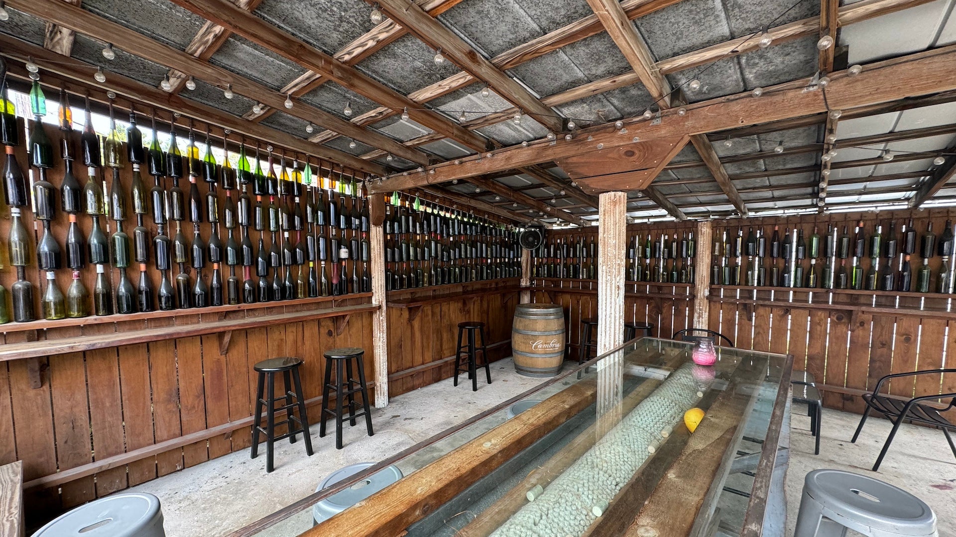 Outdoor bar area with walls covered with hanging wine bottles