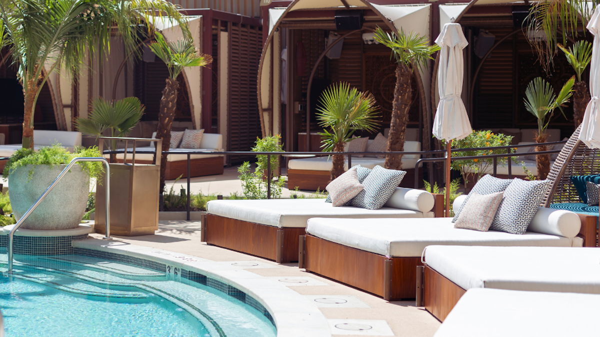 Cabana beds next to a pool with palm trees behind them