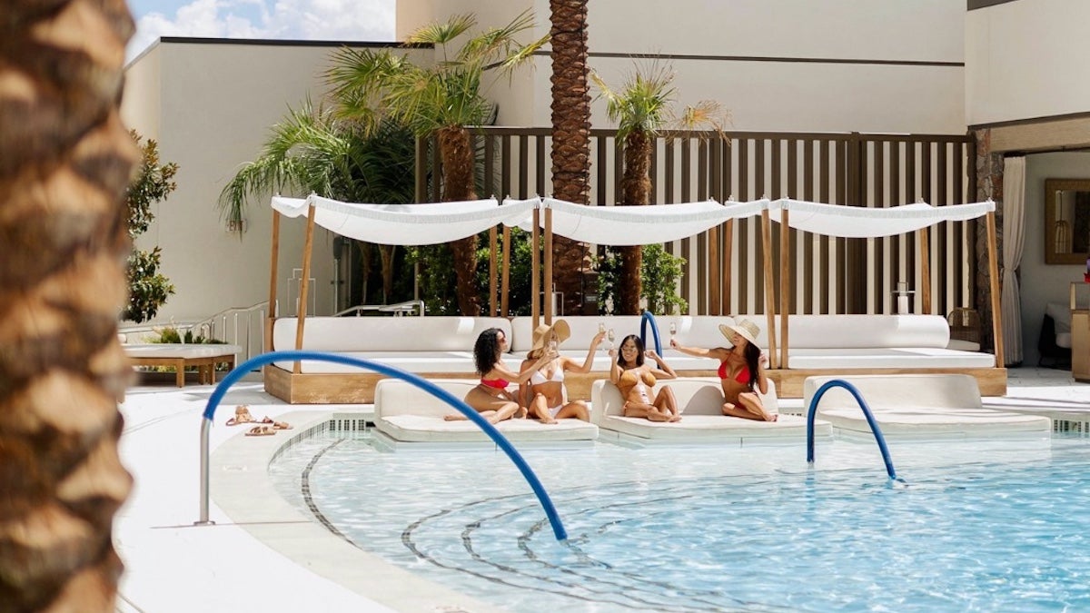 Several women clinking glasses while they lounge next to the pool