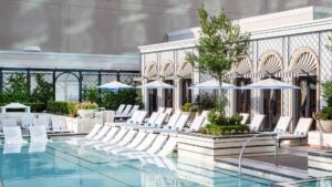 Pool with white lounge chairs and cabanas behind them