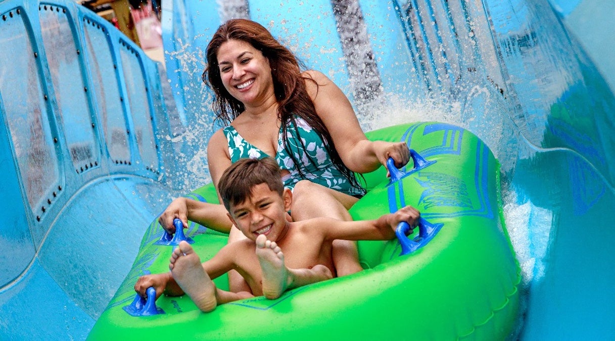 Woman with small child in a green tube going down a water slide