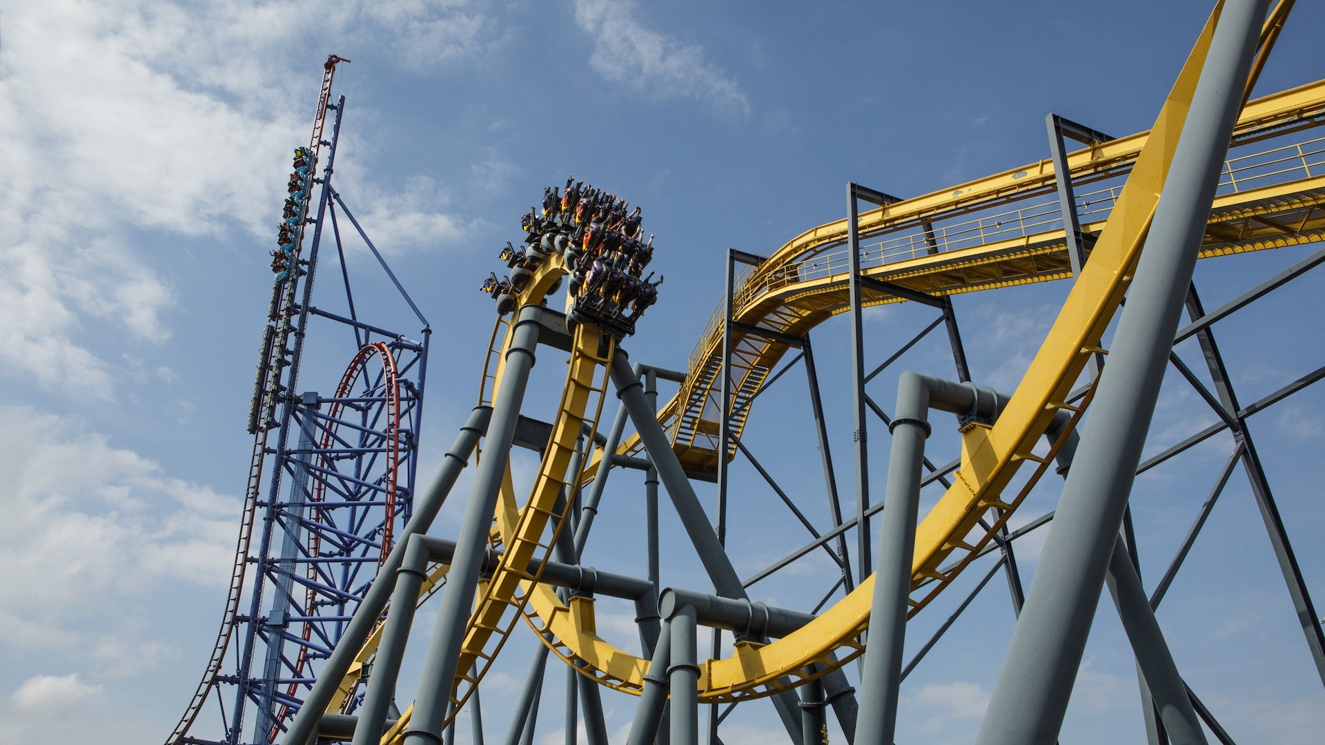 Roller coasters with riders under a blue sky