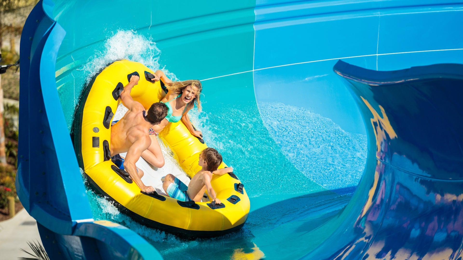 Family on a yellow tube sliding along a blue water slide