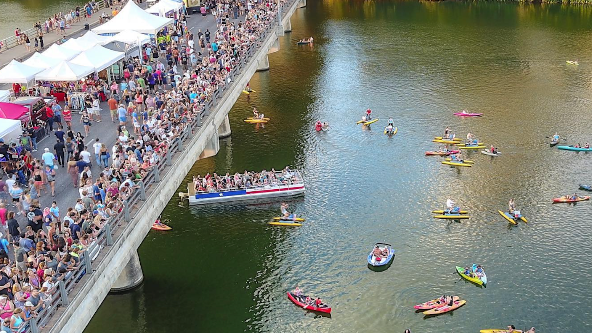 a bridge view with lots of people watching boats