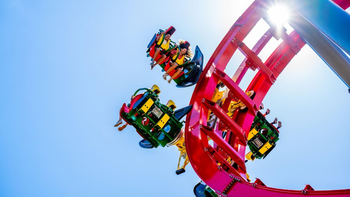 Riders experience the adrenaline rush on Adventureland’s red roller coaster, soaring through loops and twists.