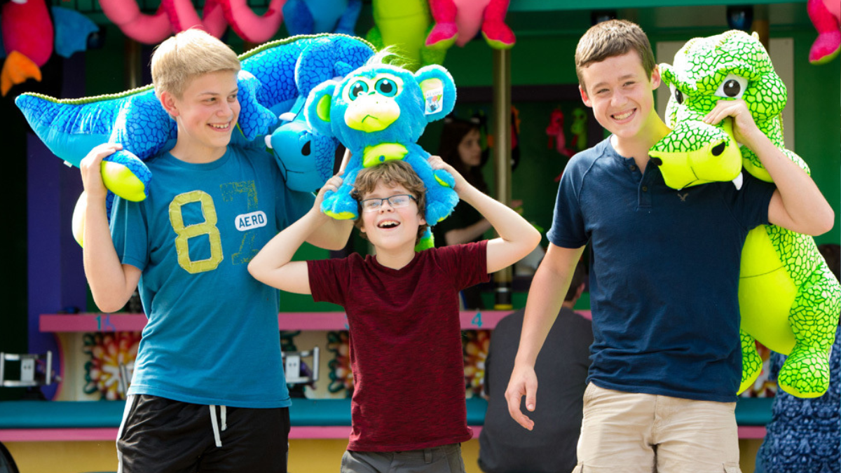 Three boys proudly displaying large stuffed animals they won at Idlewild SoakZone.