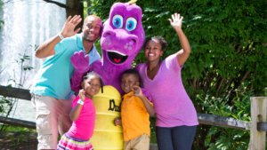 A family posing and waving with Duke the Dinosaur at Idlewild SoakZone.