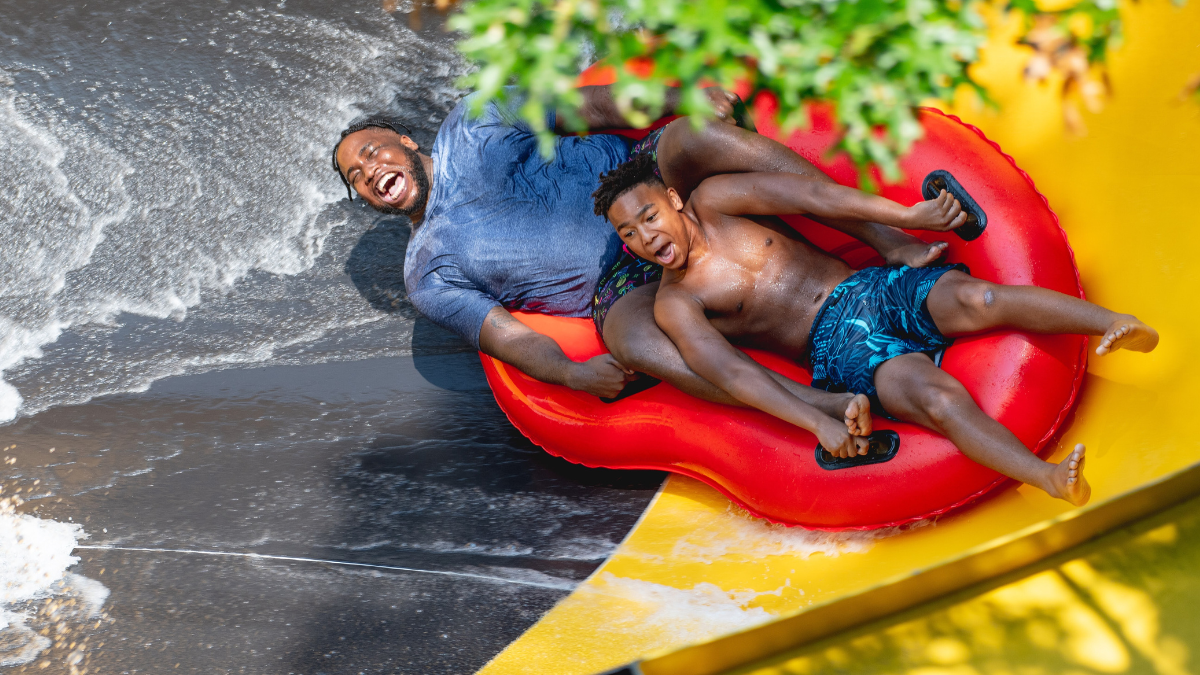 Father and son enjoying a fast ride down a water slide at Splish Splash Water Park.