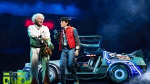 two performers on stage with a sports car prop