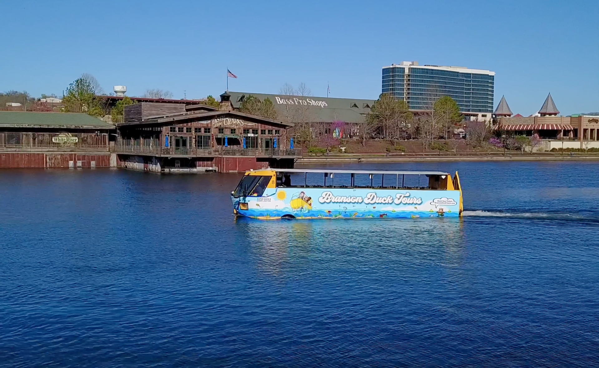 Branson duck tour vehicle in a lake with the branson landing in the background