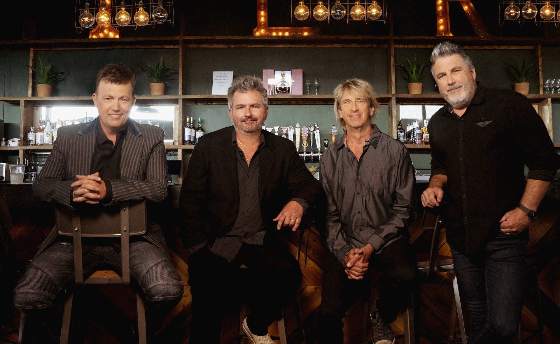 Four men in a band posing for a picture at a bar.