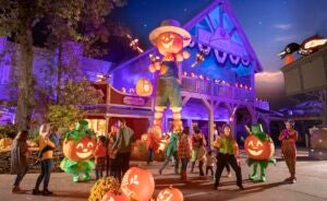 Silver dollar city decorated with fall pumpkins at dusk with a large pumpkin scarecrow surrounded by people